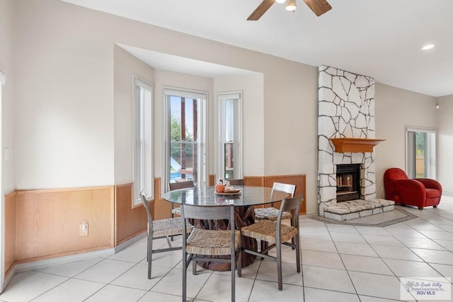 tiled dining room featuring a wood stove and ceiling fan