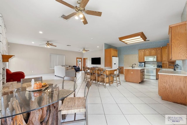 tiled dining space with ceiling fan and sink