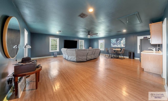 living room featuring sink, light hardwood / wood-style floors, a wealth of natural light, and ceiling fan