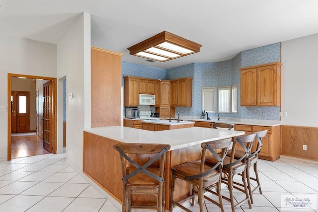 kitchen featuring kitchen peninsula, a kitchen breakfast bar, light tile patterned floors, and a healthy amount of sunlight