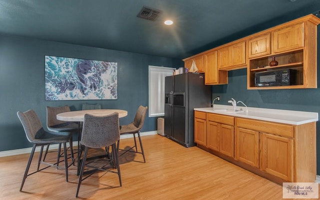 kitchen with black appliances, sink, and light hardwood / wood-style flooring