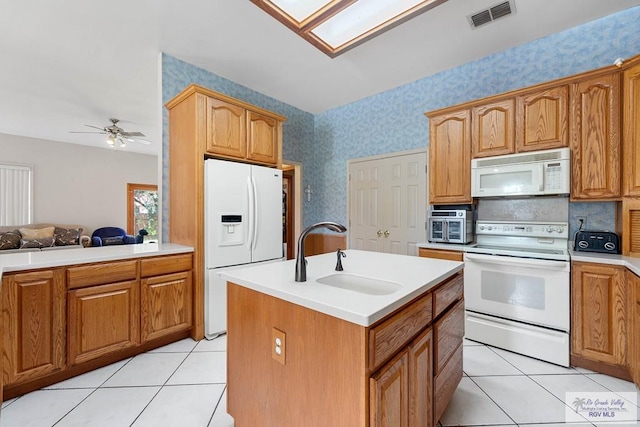 kitchen featuring white appliances, ceiling fan, a kitchen island with sink, sink, and light tile patterned floors