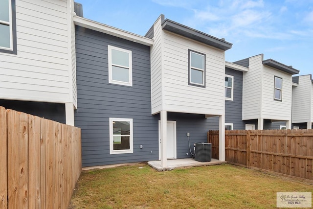 rear view of house featuring central air condition unit, a lawn, a patio, and a fenced backyard