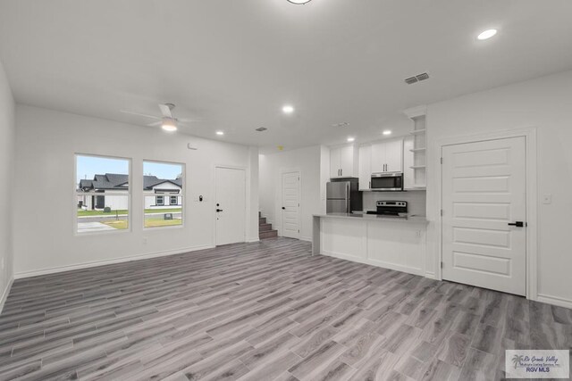 unfurnished living room featuring stairway, visible vents, light wood finished floors, recessed lighting, and ceiling fan