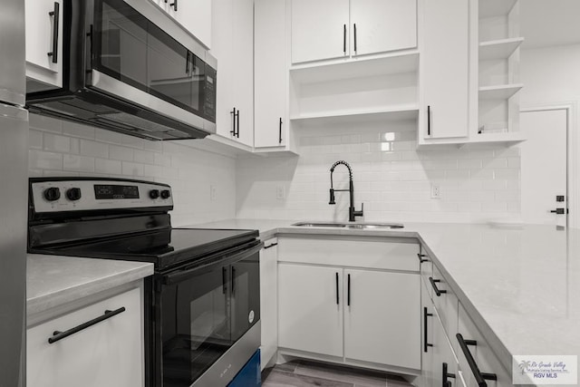 kitchen with open shelves, light countertops, appliances with stainless steel finishes, white cabinets, and a sink