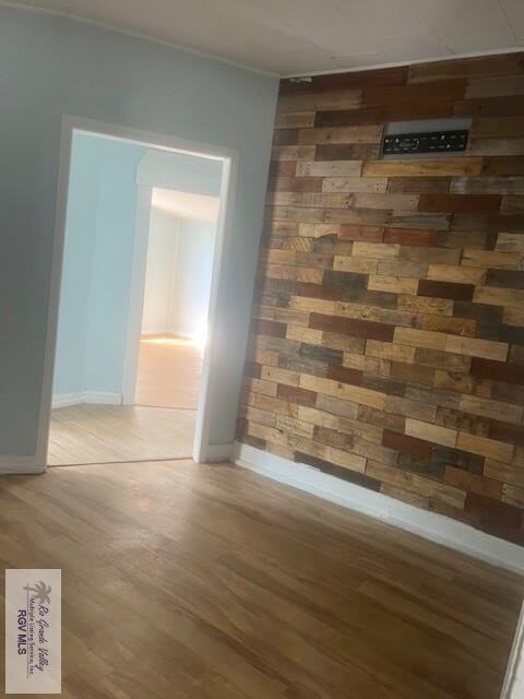 spare room with baseboards, wooden walls, and wood finished floors