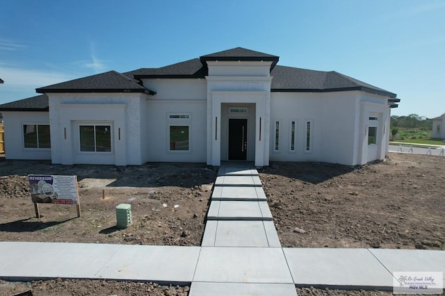 view of front of home featuring a shingled roof and stucco siding