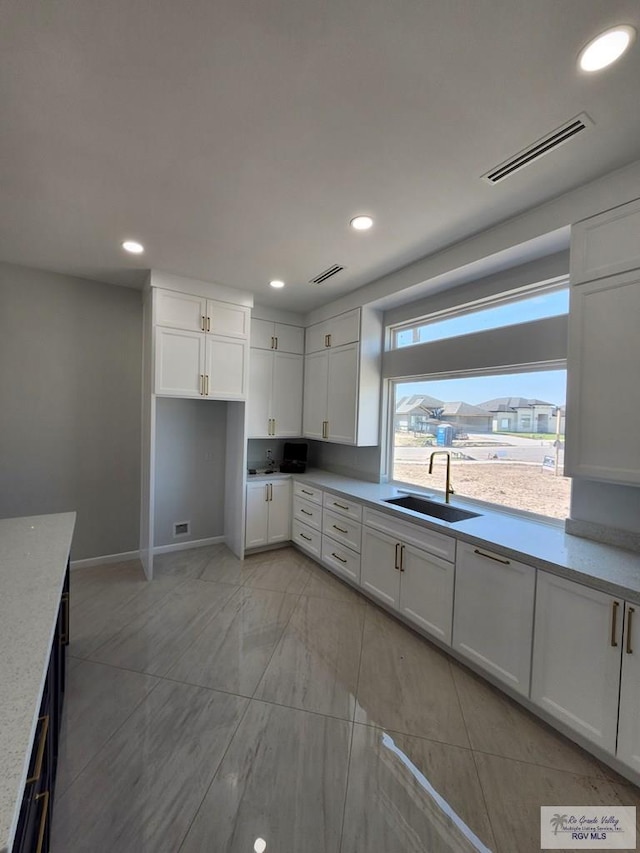 kitchen featuring recessed lighting, a sink, visible vents, and white cabinets