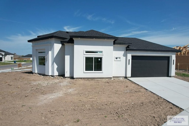 view of front facade with an attached garage, a shingled roof, concrete driveway, and stucco siding