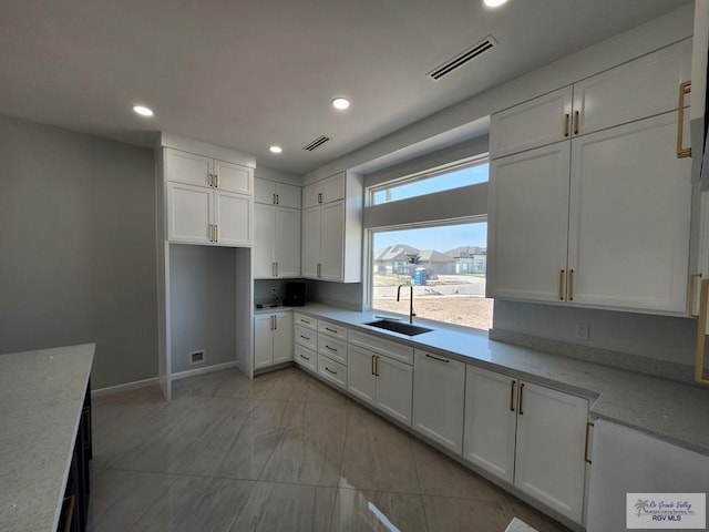 kitchen with recessed lighting, a sink, visible vents, baseboards, and white cabinetry