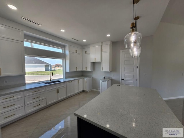 kitchen with visible vents, light stone counters, white cabinetry, a sink, and recessed lighting