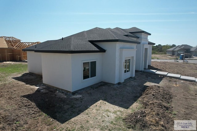 view of home's exterior with a shingled roof and stucco siding