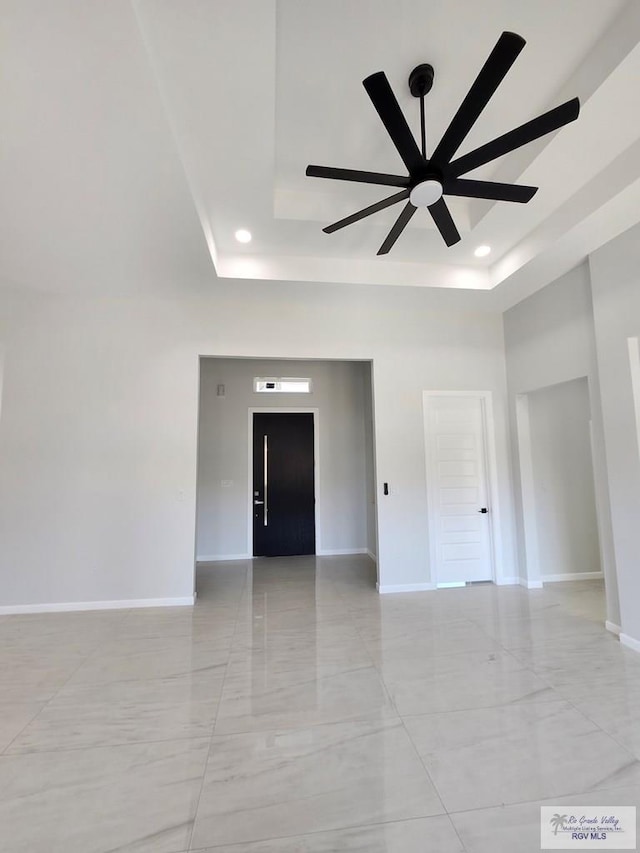 empty room featuring baseboards, a tray ceiling, and a ceiling fan