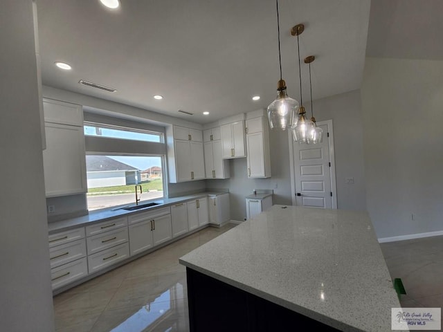 kitchen featuring visible vents, white cabinets, light stone countertops, a sink, and recessed lighting