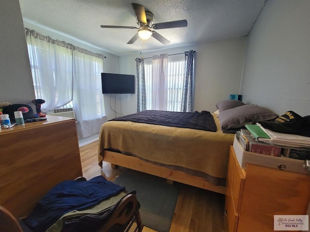 bedroom featuring ceiling fan, light hardwood / wood-style flooring, and a textured ceiling