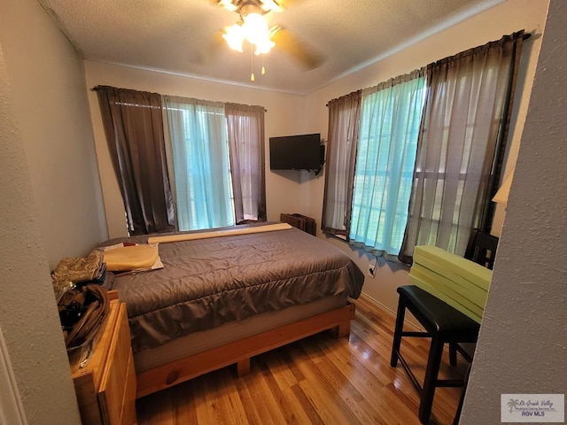 bedroom featuring hardwood / wood-style flooring, ceiling fan, and a textured ceiling