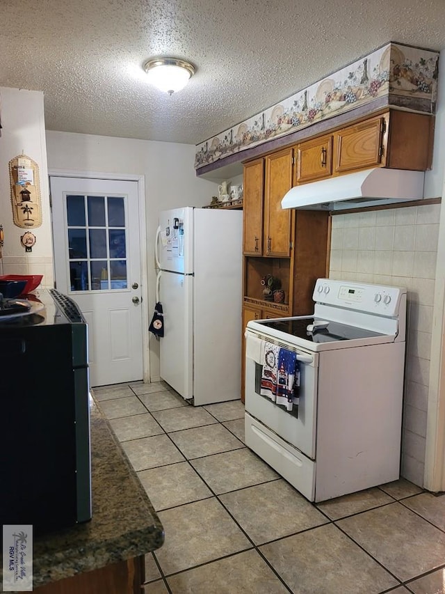 kitchen featuring a textured ceiling, light tile patterned floors, and white appliances