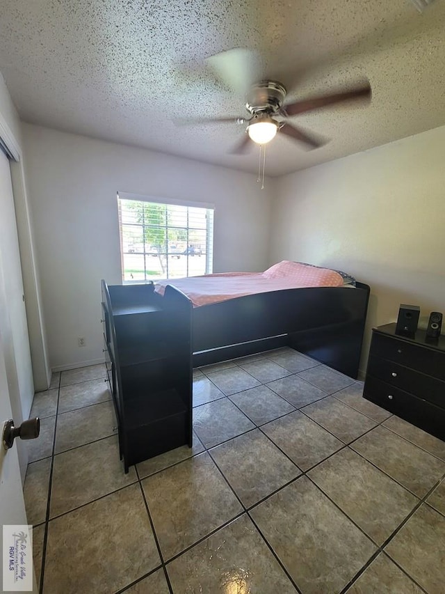 bedroom featuring tile patterned flooring, a textured ceiling, and ceiling fan