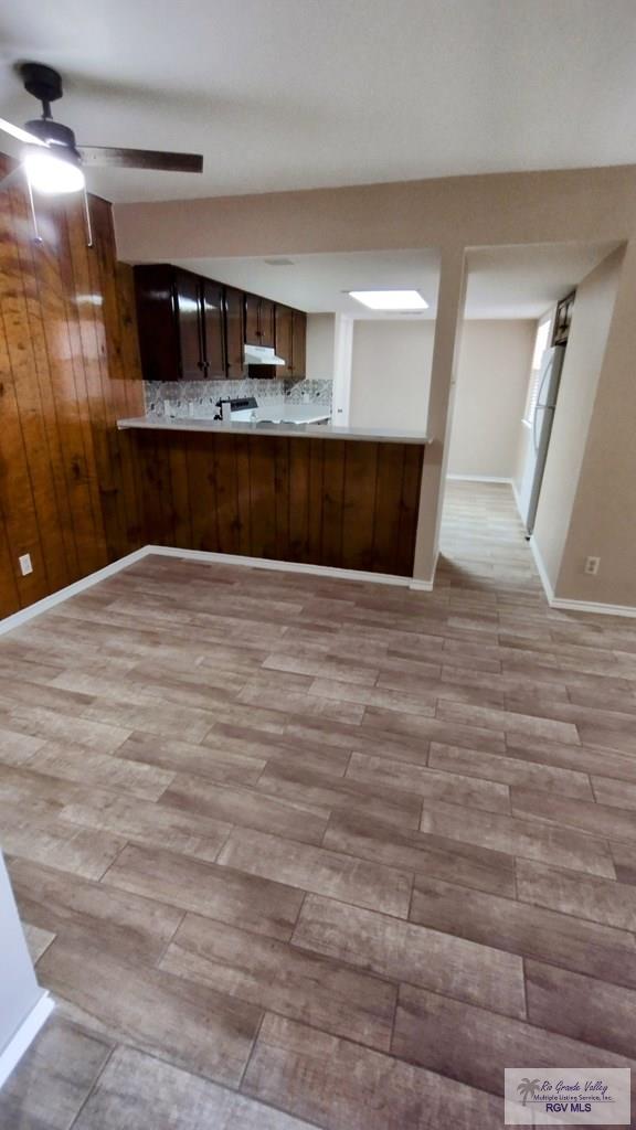 kitchen featuring kitchen peninsula, ceiling fan, dark brown cabinetry, and light wood-type flooring