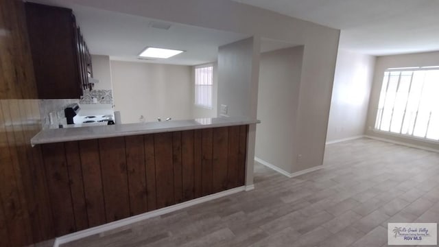 kitchen with kitchen peninsula, range with electric cooktop, light hardwood / wood-style flooring, and dark brown cabinets