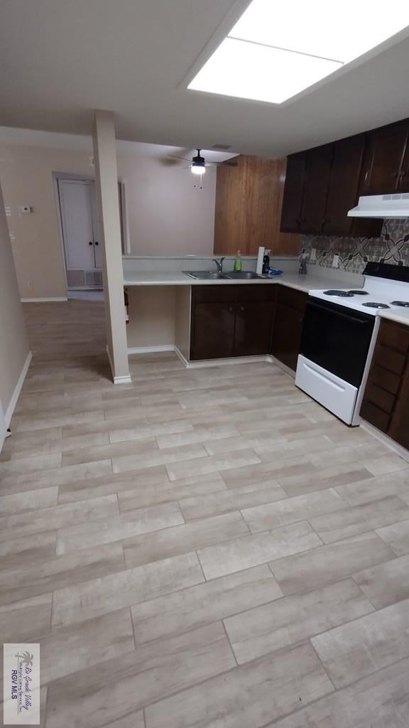 kitchen with backsplash, sink, white range with electric stovetop, light hardwood / wood-style floors, and dark brown cabinets