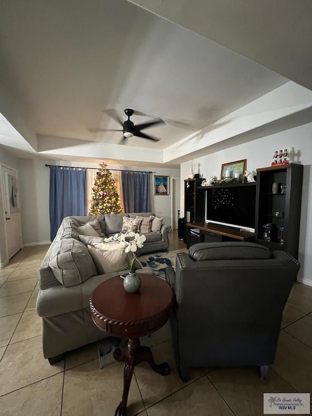 living room featuring a tray ceiling, ceiling fan, and tile patterned floors