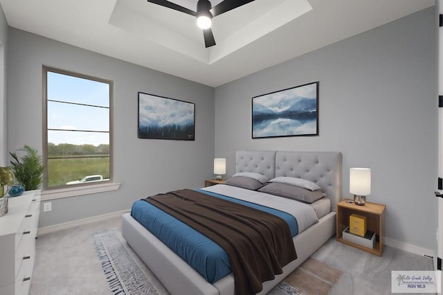 bedroom featuring ceiling fan, a raised ceiling, and light carpet