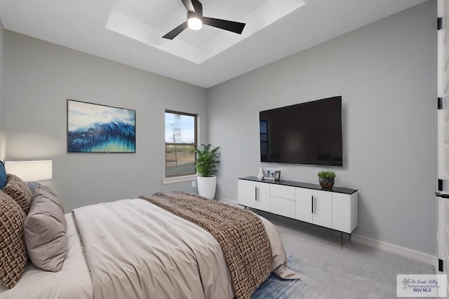 carpeted bedroom with ceiling fan and a tray ceiling