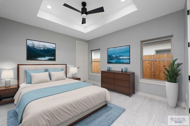 bedroom with ceiling fan and a tray ceiling