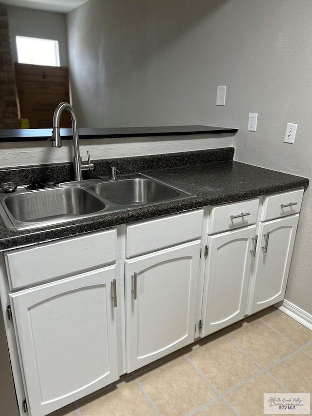 kitchen featuring white cabinets, light tile patterned flooring, and sink