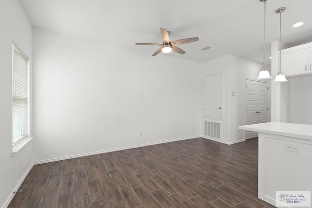 unfurnished living room featuring ceiling fan and dark wood-type flooring