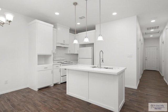 kitchen with white appliances, a kitchen island with sink, sink, dark hardwood / wood-style floors, and decorative light fixtures