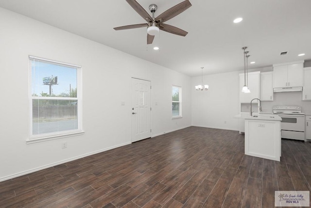 unfurnished living room featuring a wealth of natural light, sink, ceiling fan with notable chandelier, and dark hardwood / wood-style floors