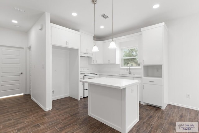 kitchen with sink, dark wood-type flooring, a kitchen island, white range with electric stovetop, and white cabinets