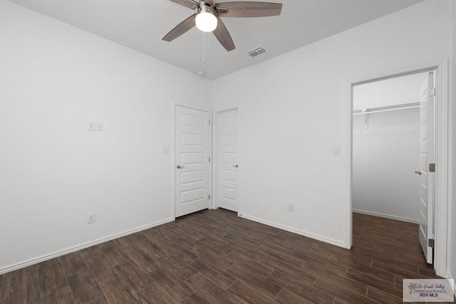 unfurnished bedroom with ceiling fan, dark hardwood / wood-style floors, a spacious closet, and a closet