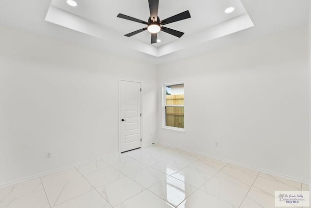 empty room featuring ceiling fan and a raised ceiling