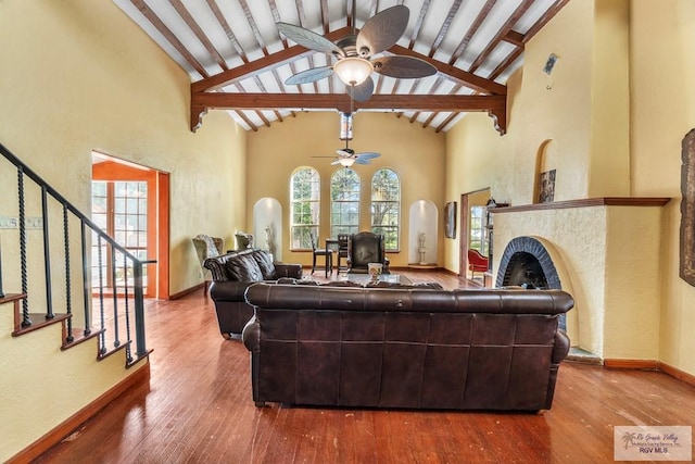 living room with hardwood / wood-style flooring, beamed ceiling, high vaulted ceiling, and ceiling fan