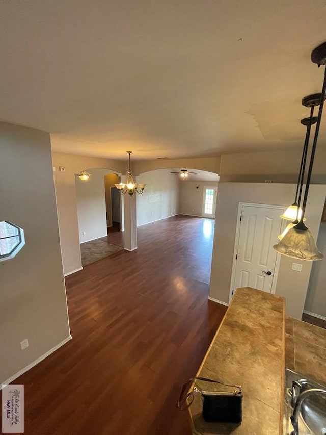 living room with ceiling fan with notable chandelier, dark hardwood / wood-style flooring, and vaulted ceiling