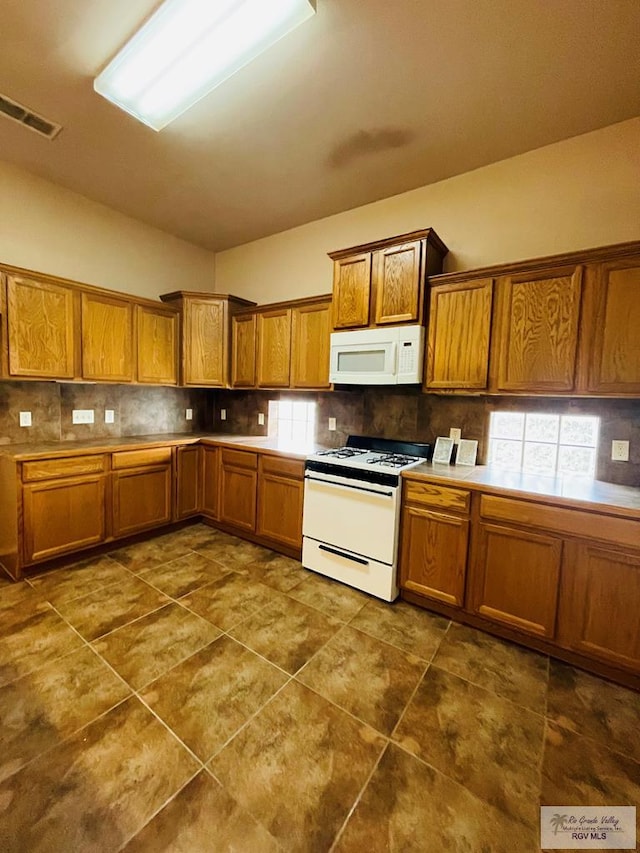 kitchen with white appliances, tasteful backsplash, and dark tile patterned floors