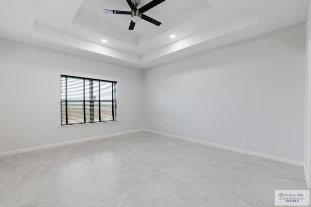 unfurnished room featuring ceiling fan and a tray ceiling