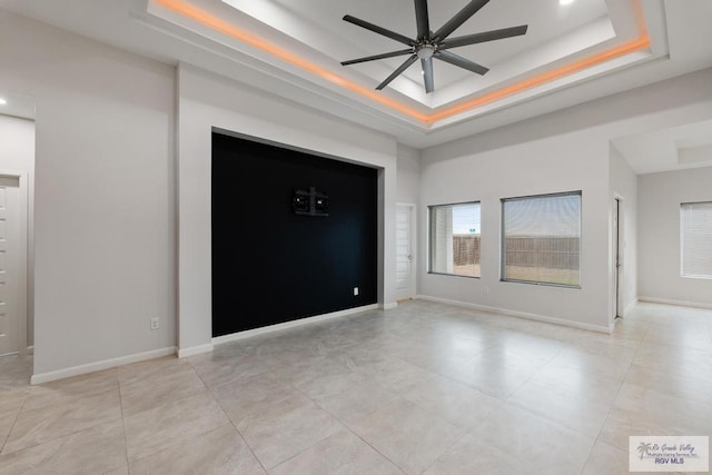 empty room featuring a raised ceiling and ceiling fan