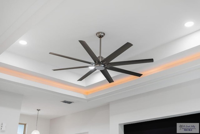 details featuring ceiling fan and a tray ceiling