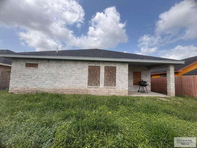6692 Los Lobos Dr, Brownsville, TX 78521 - rear view of house with a patio, stone siding, and roof with shingles