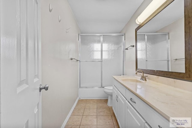 bathroom with tile patterned floors, toilet, combined bath / shower with glass door, baseboards, and vanity