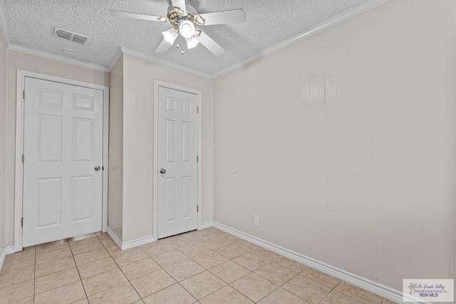 unfurnished bedroom with light tile patterned floors, visible vents, a textured ceiling, and ornamental molding