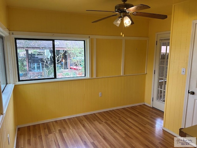 spare room featuring ceiling fan, baseboards, and wood finished floors