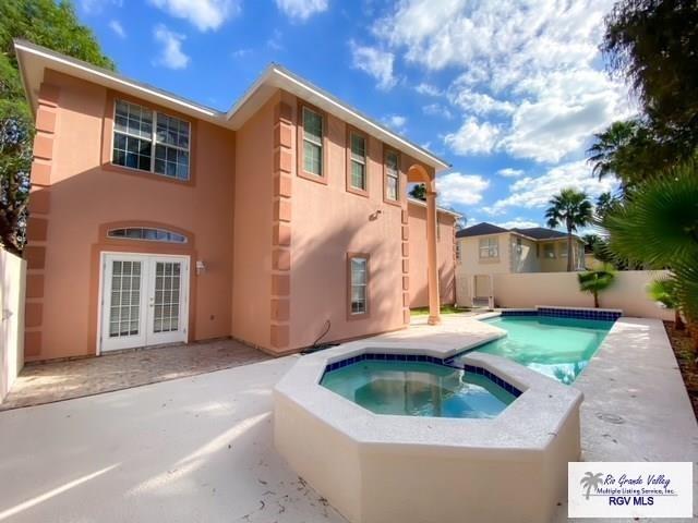 144 Country Club Rd Unit 1, Brownsville, TX 78520 - rear view of house featuring a fenced backyard, stucco siding, a patio, an in ground hot tub, and french doors