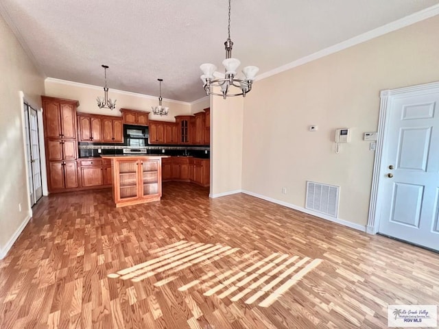 144 Country Club Rd Unit 1, Brownsville, TX 78520 - kitchen featuring light wood-style flooring, visible vents, a kitchen island, a chandelier, and dark countertops