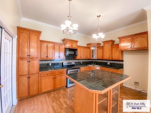 144 Country Club Rd Unit 1, Brownsville, TX 78520 - kitchen with black microwave, brown cabinetry, a chandelier, a sink, and stainless steel electric range