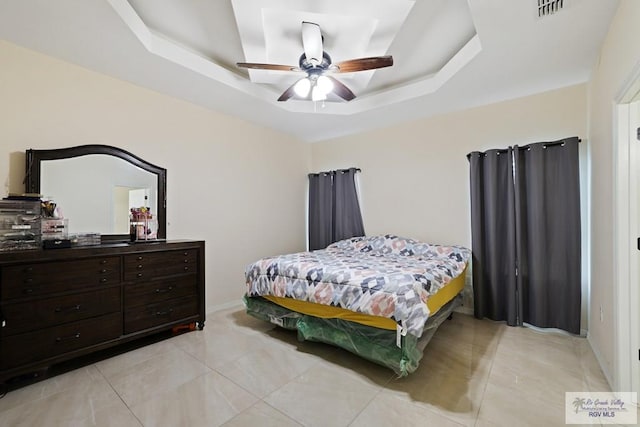bedroom with light tile patterned floors, ceiling fan, a tray ceiling, visible vents, and baseboards